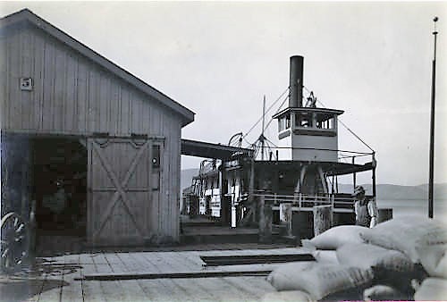 A steam ship at a wharf, another man walking in front, at San Quentin prison.