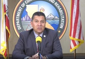 COVID-19 update from Secretary Ralph Diaz as he sits in front of CDCR logo and two flags.