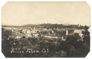 Prison buildings surrounded by hills and trees. "Prison, Folsom, Cal." is written on the image.