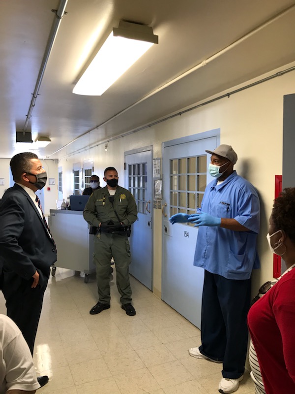CDCR Secretary Diaz visited three prisons to speak with staff and the incarcerated population during COVID-19. He's seen here with others wearing masks while standing in a hallway.