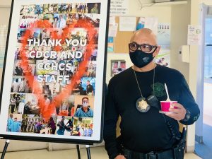 Correctional sergeant holds frozen yogurt while standing beside a sign that reads "Thank you CDCR and CCHCS staff."