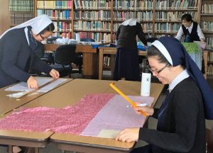 Nuns work in a library to make masks.