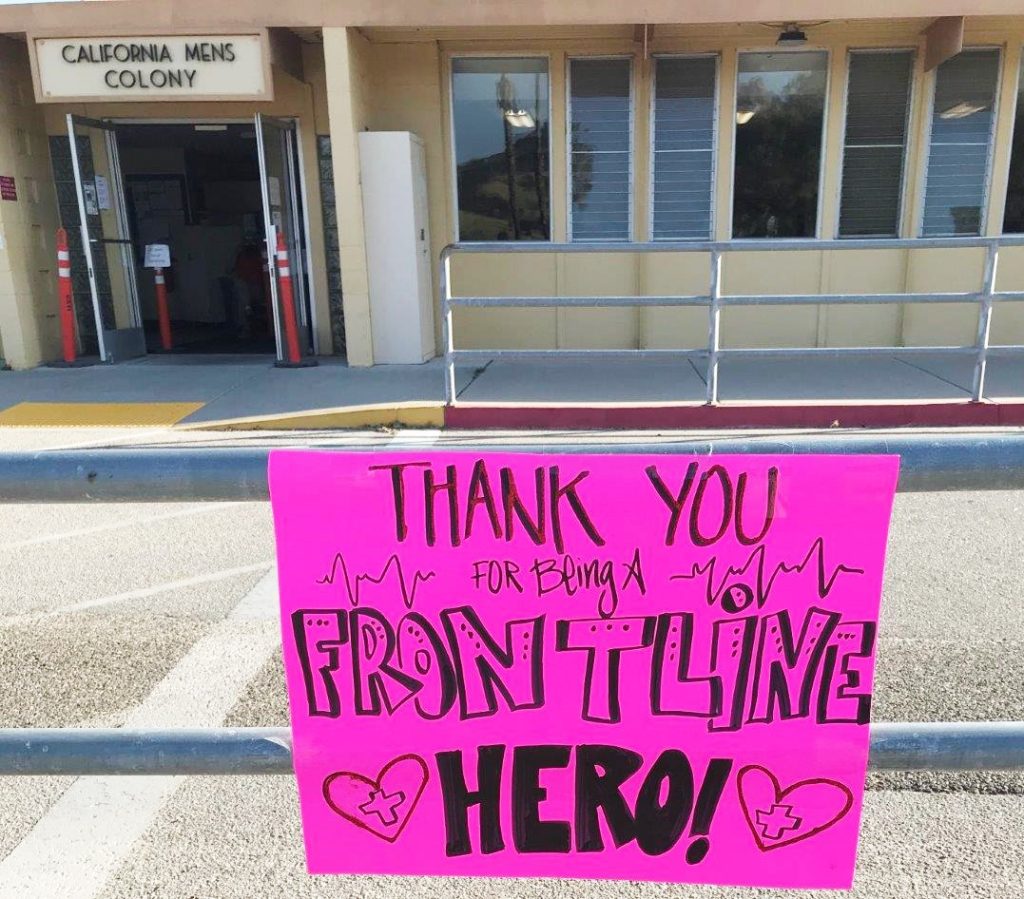 A sign in front of California Men's Colony says "thank you for being a front line hero."