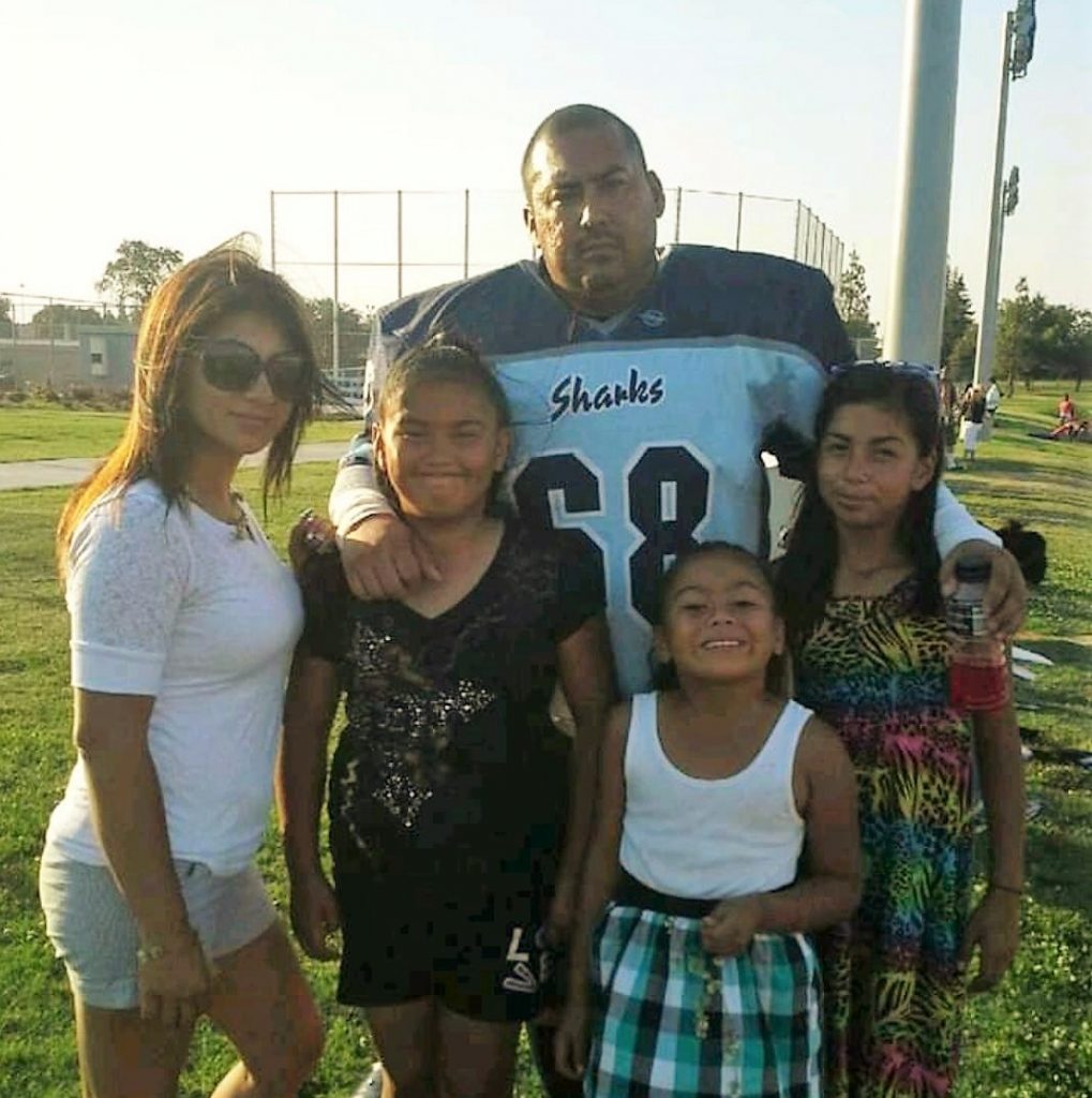 Man in football uniform with his kids and wife.