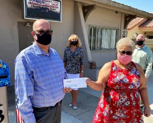 A man hands a check to a woman while two others look on.