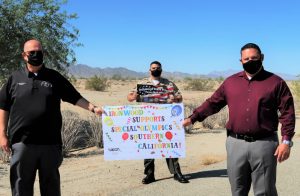 Three men hold signs saying Ironwood State Prison supports Special Olympics.