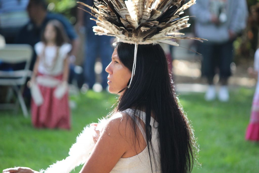 Native American woman wears a feathered headdress.