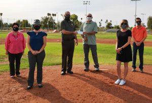 Six people wearing mask. One is handing a check to another