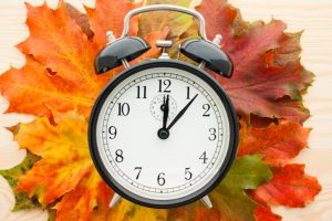 Daylight saving time graphic shows clock and fall leaves.