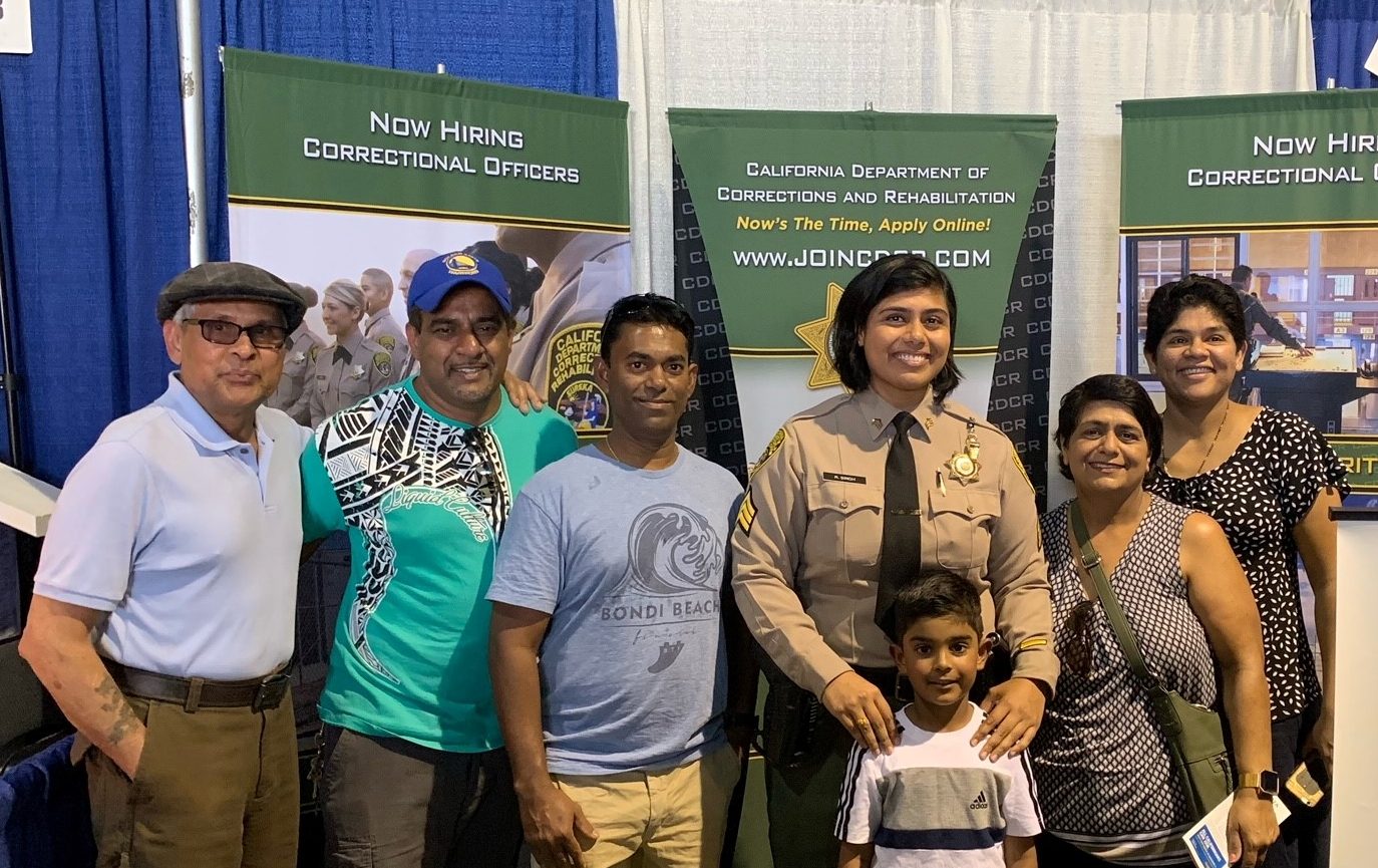 Sgt. Singh at a CDCR recruitment booth surrounded by her family.
