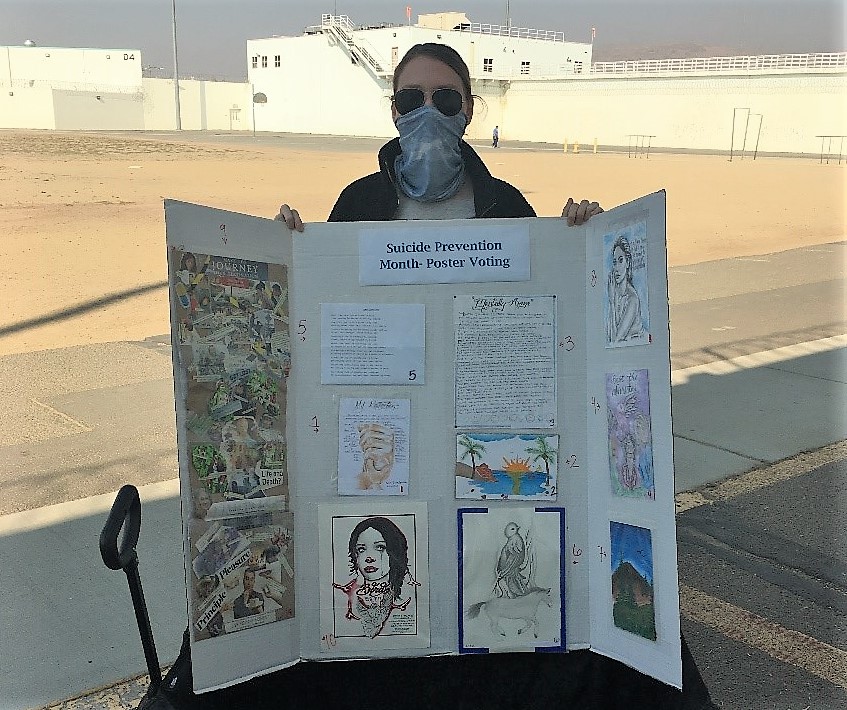 A staff member at High Desert State Prison displays posters on a board.