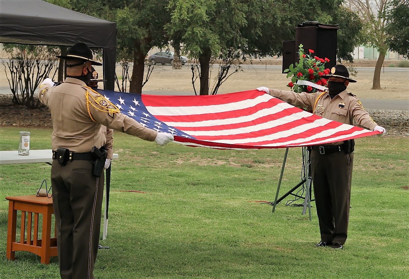 Avenal State Prison Honor Guard members begin folding a flag.