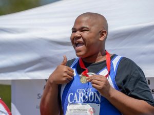 Special Olympics athlete smiles and gives a thumbs up.