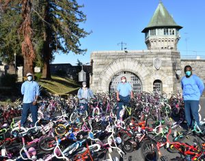 Four incarcerated men at Folsom Prison stand amid more than 50 bicycles.