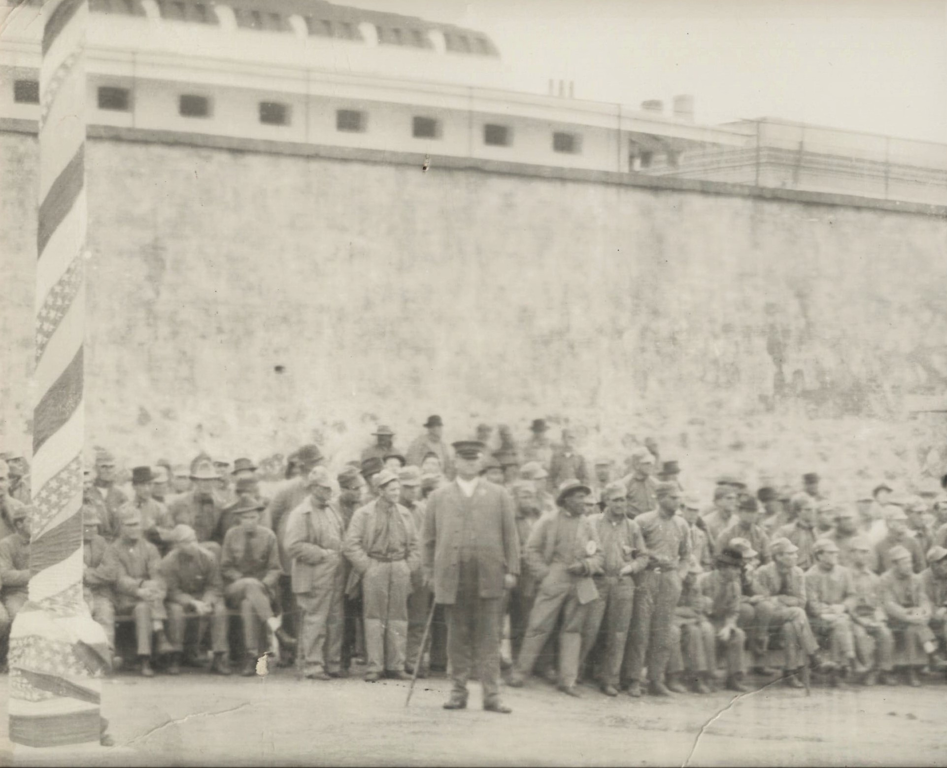 San Quentin inmates watch a baseball game while a guard supervises.