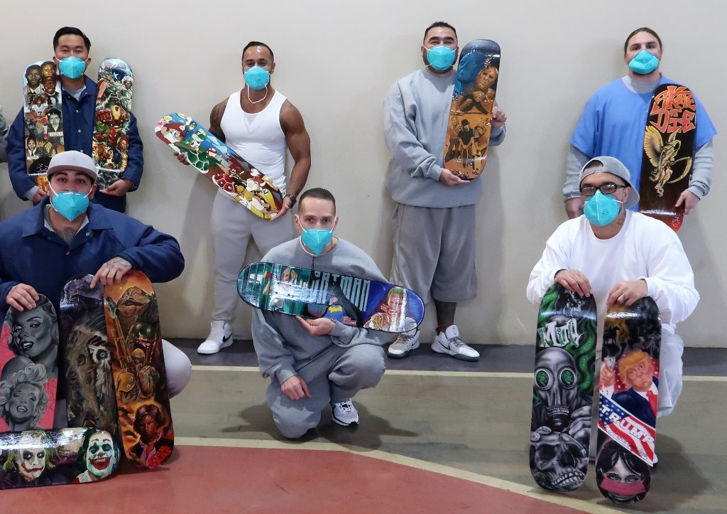 ASP incarcerated artists hold painted skateboards.