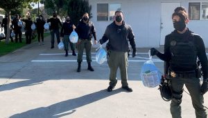 Line of CDCR officers each holding a frozen turkey.