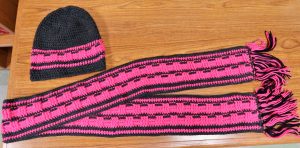 A pink hat and scarf knitted and crocheted by four people at Avenal State Prison.