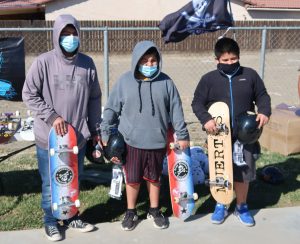 Three Avenal kids hold donated incarcerated artists' skateboards.
