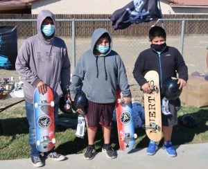 Three Avenal kids hold donated incarcerated artists' skateboards.