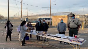 Prison staff stand by tables of baked goods.