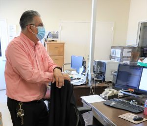 A man wearing a mask oversees an eyeglass project in a prison.