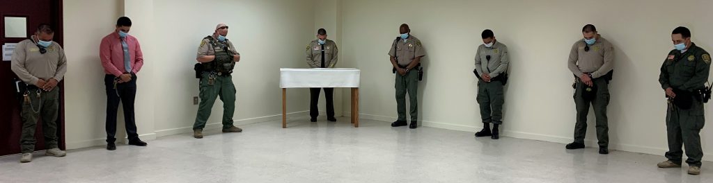 Prison staff bow their heads in a moment of silence.