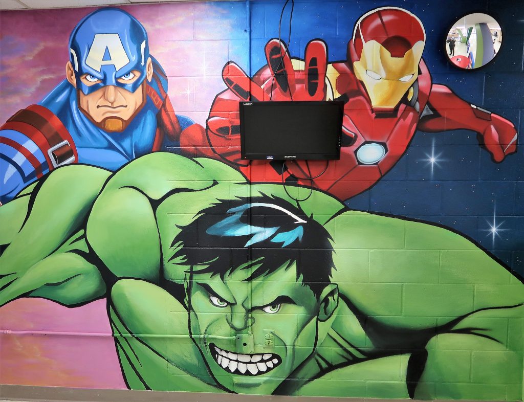 Paintings of the Hulk, Iron Man and Captain America on a prison visiting area wall.