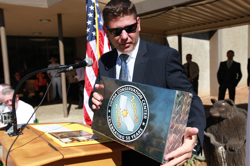 Man holds a metal box with the words Sierra Conservation Center 1965-2015 Celebrating 50 years.
