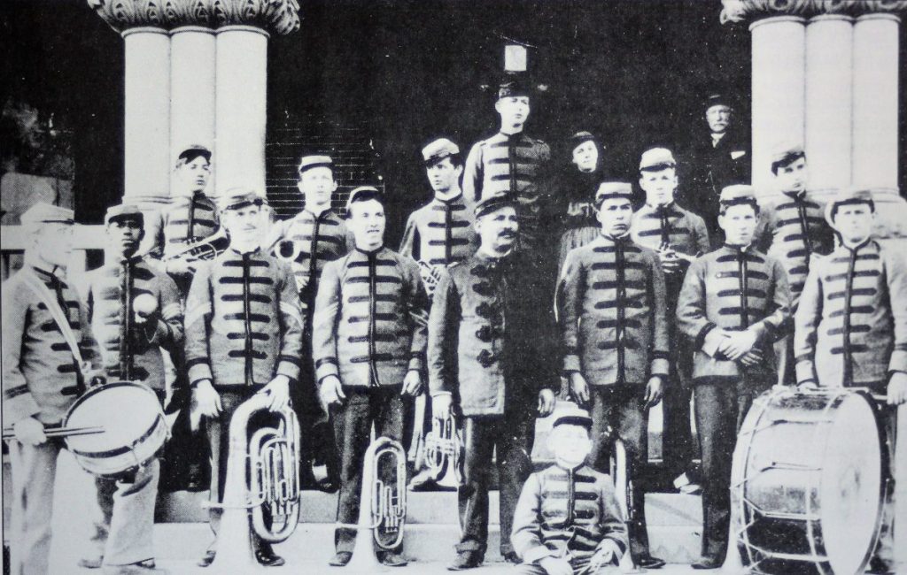 Preston School band students wear uniforms and stand on steps.