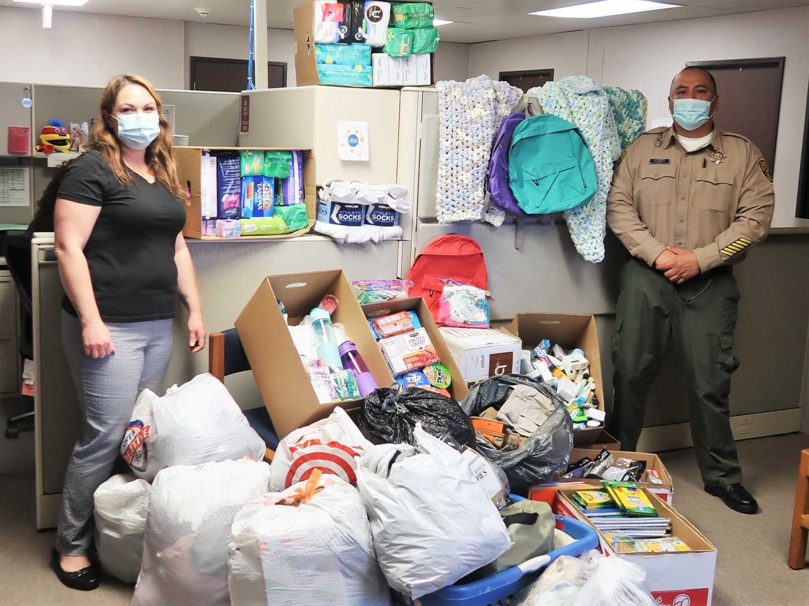 Donations for foster youth with two prison staff members standing beside it.