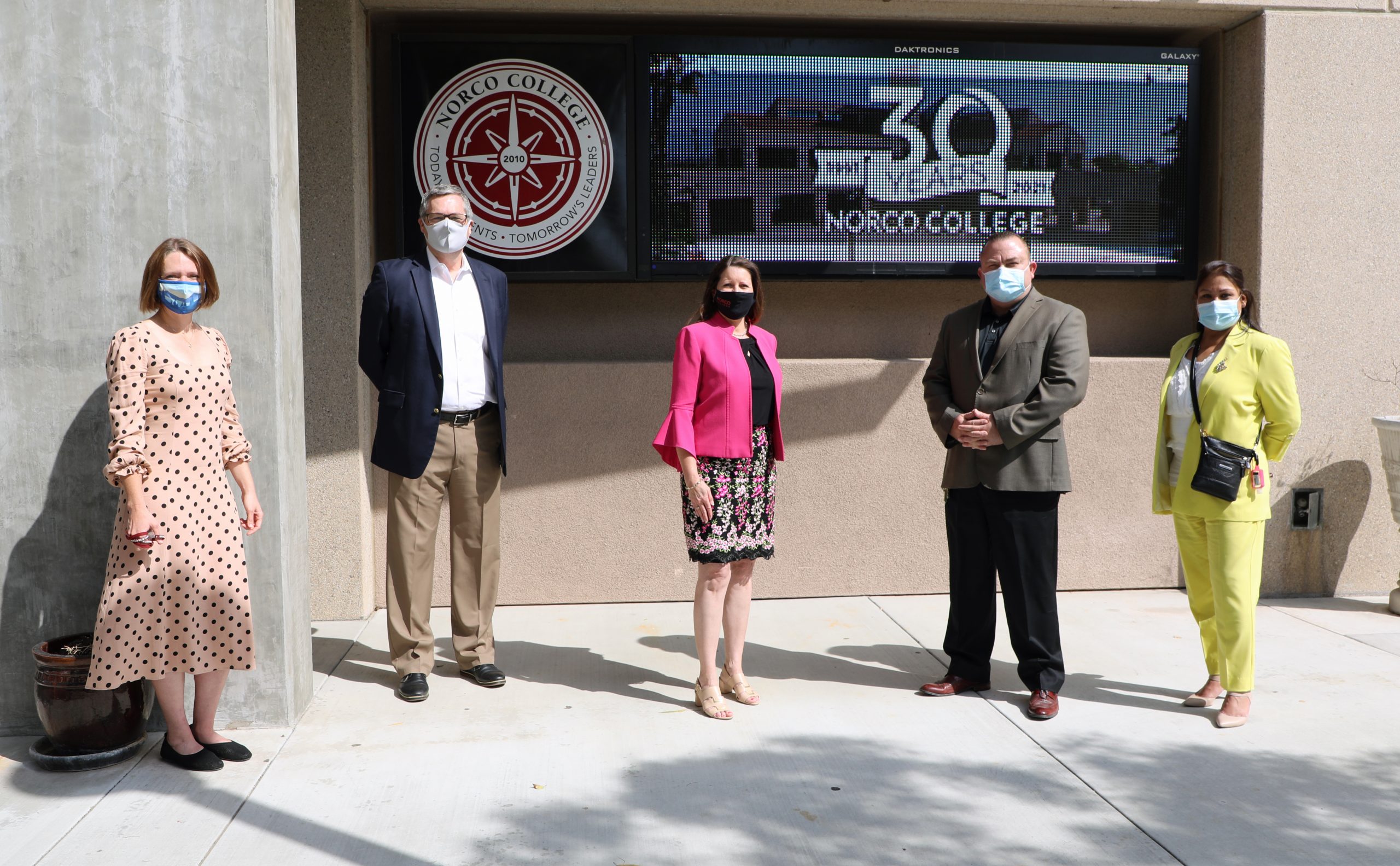 Five people stand in front of a Norco College building.