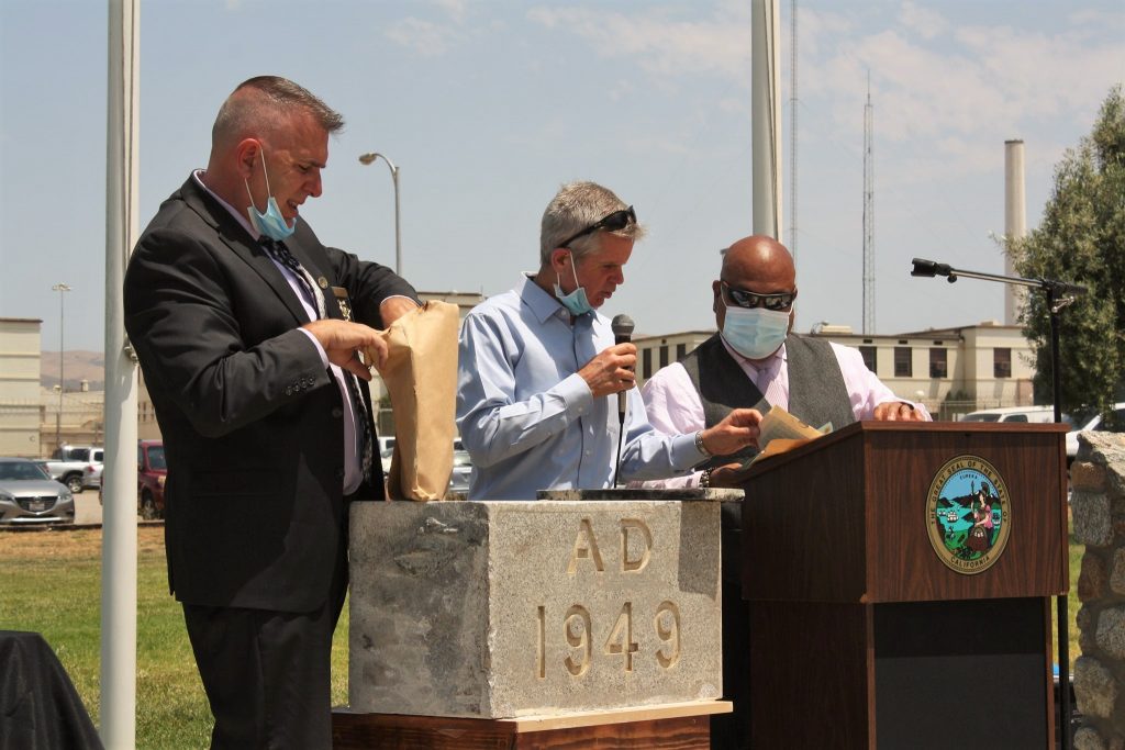 Three people open a time capsule at a ceremony marking 75 years.