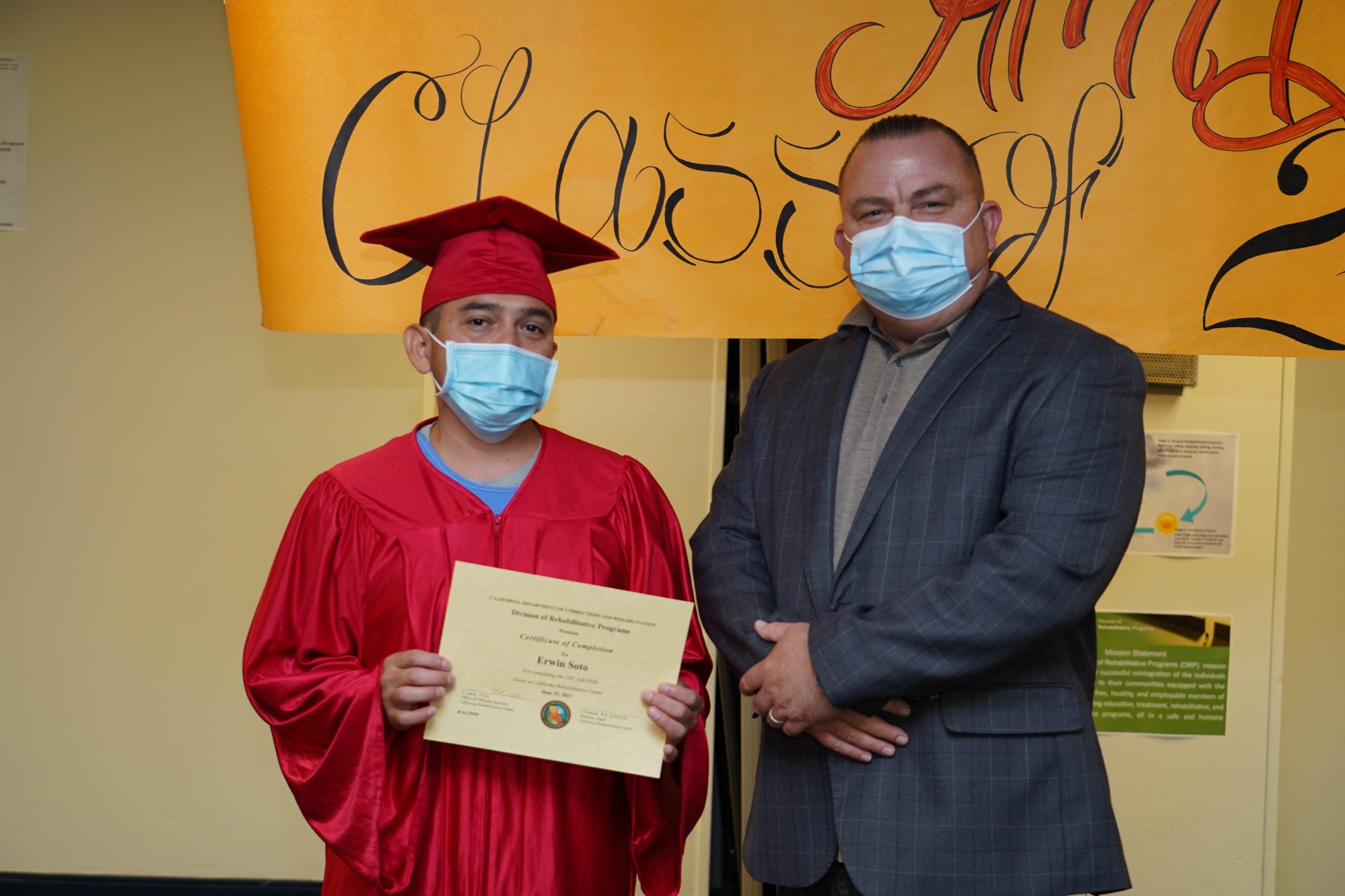 graduate and prison warden hold certificate.