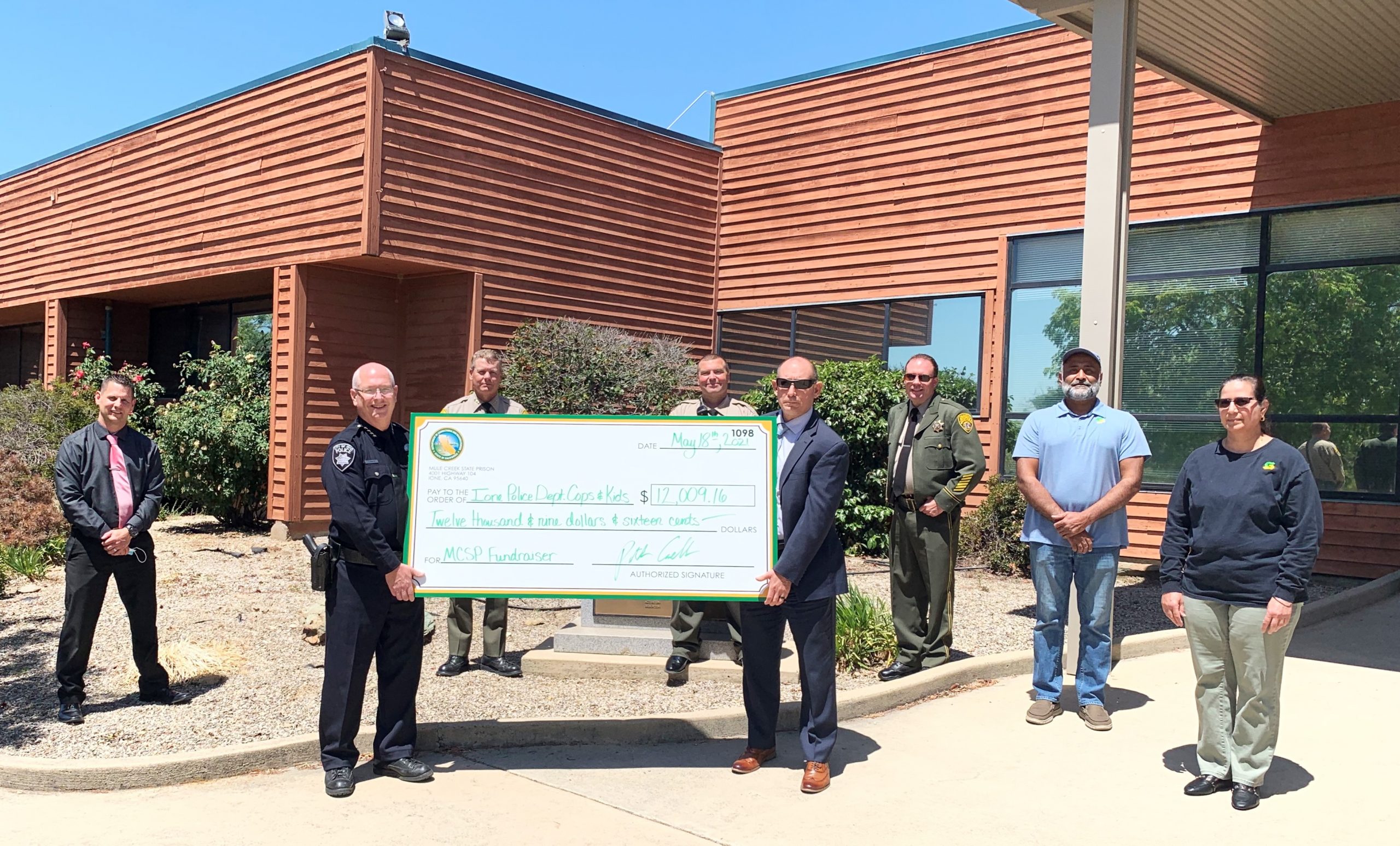 Mule Creek prison staff give a check to police chief to benefit youth.