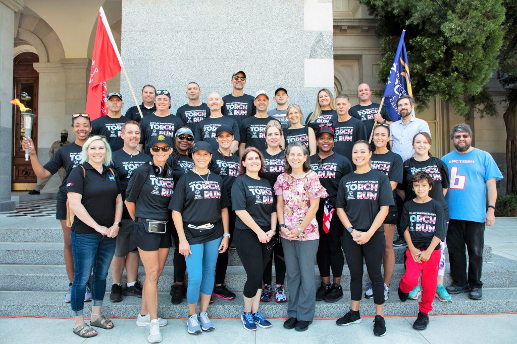People wear Torch Run t-shirts while stands on steps of the state Capitol.