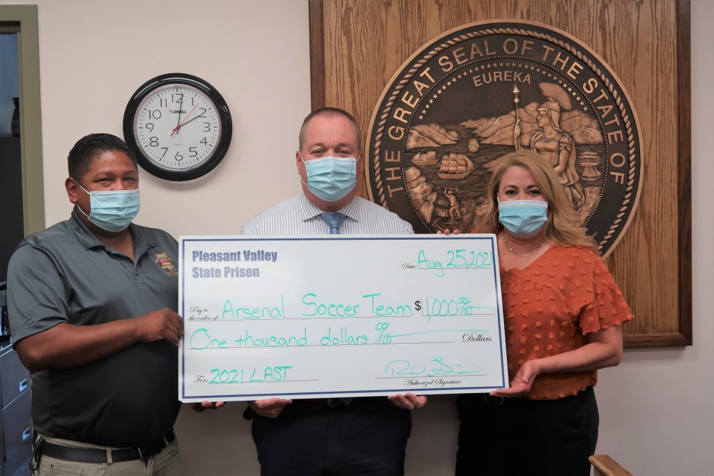 Prison staff present a check to a soccer group.