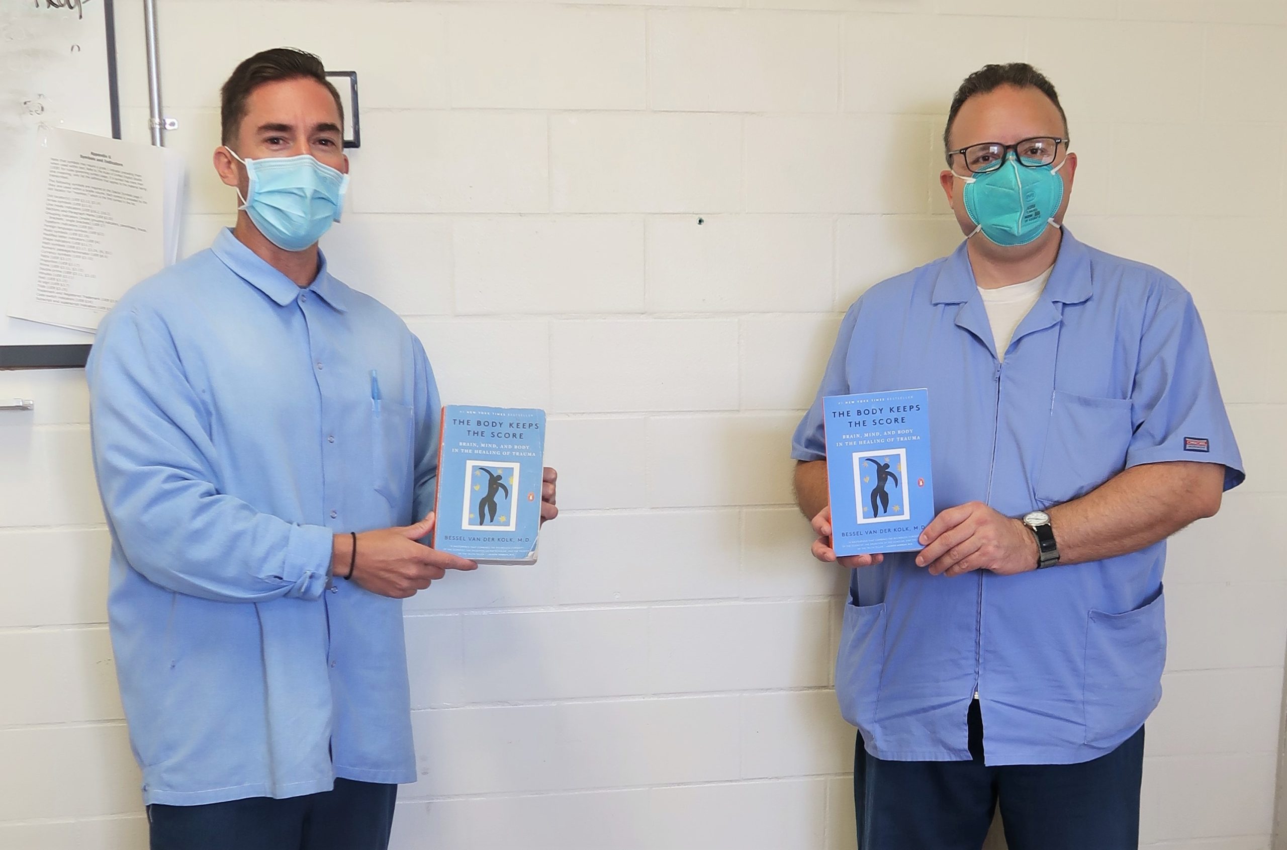 Two CMF inmates hold a book called "The Body Keeps the Score."