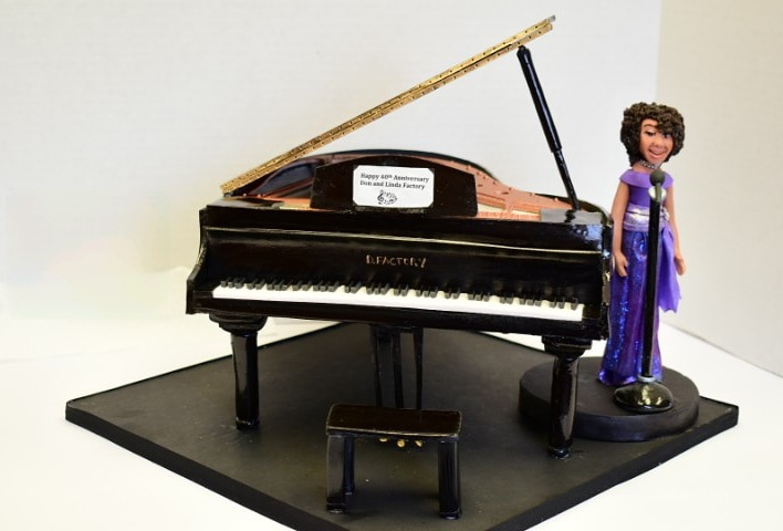 A cake styled as a piano and woman.