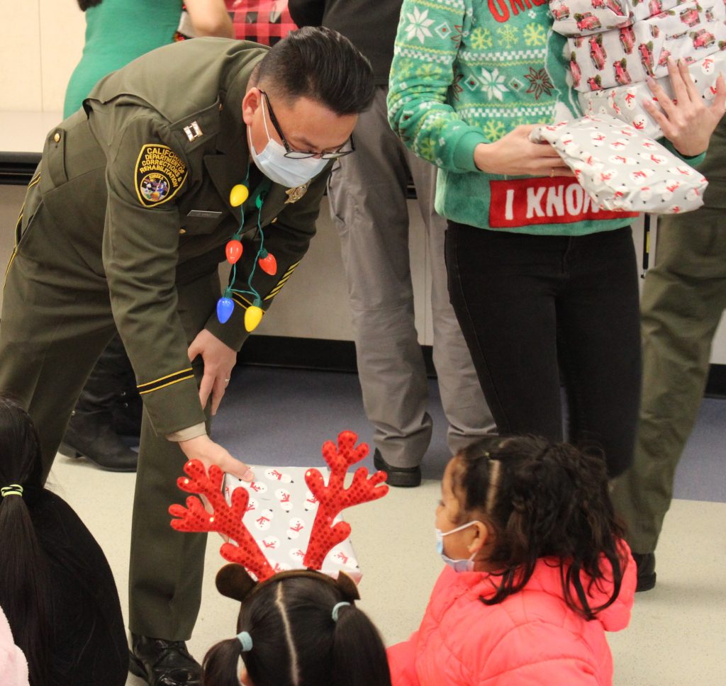 Correctional officers hands a gift to a child.