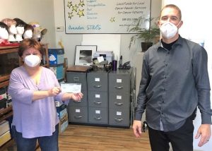 Amador Stars office worker holds check presented by Mule Creek staff member.