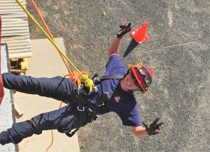 Fire Captain Kelly Witt on ropes rappelling down a building.