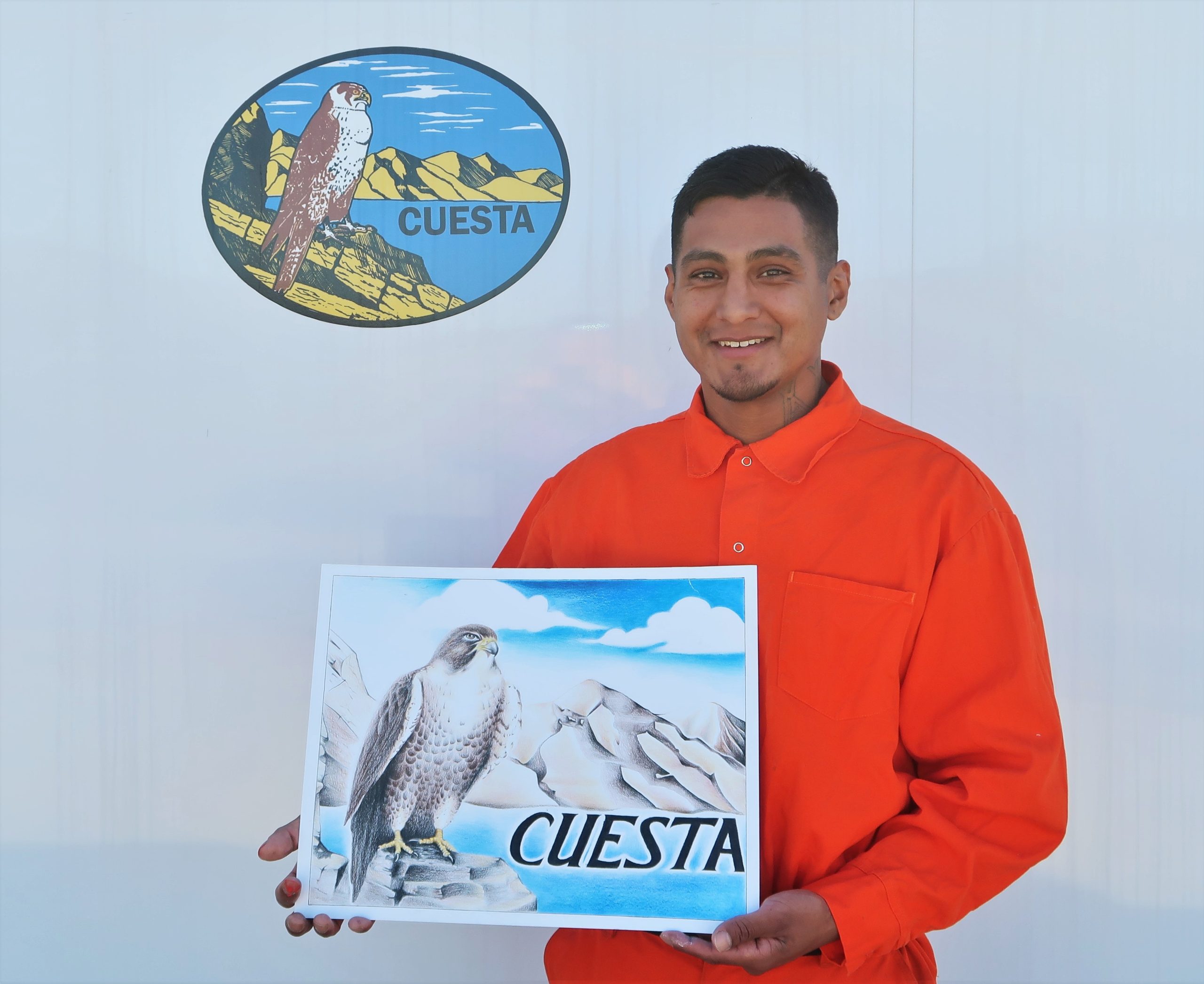 Camp Cuesta firefighter artist holds drawing of falcon mascot.