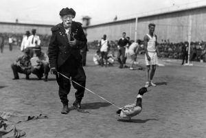 A clown is walking a pet duck at San Quentin.