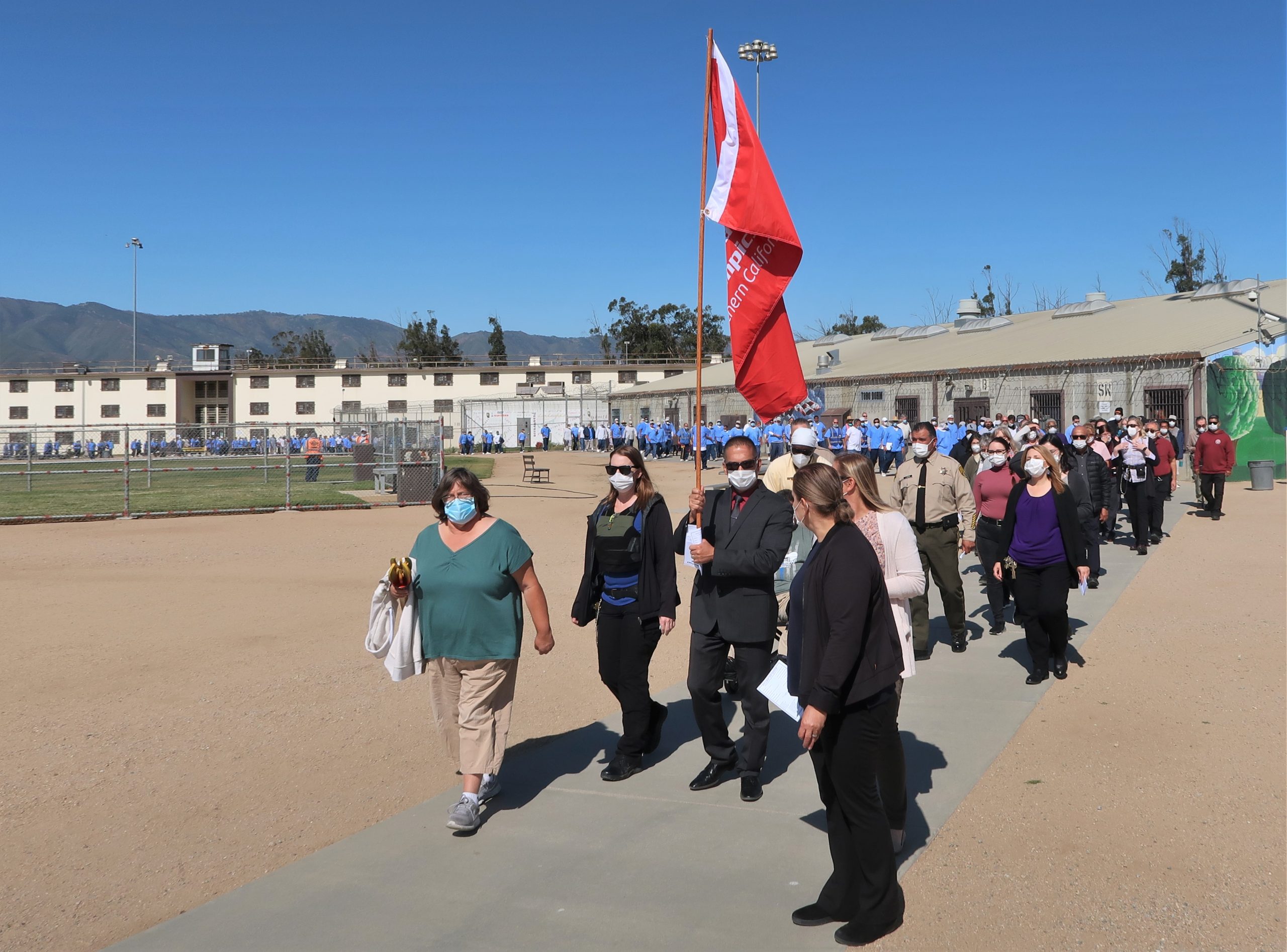 Prison inmates, warden walk while carrying a Special Olympics flag.