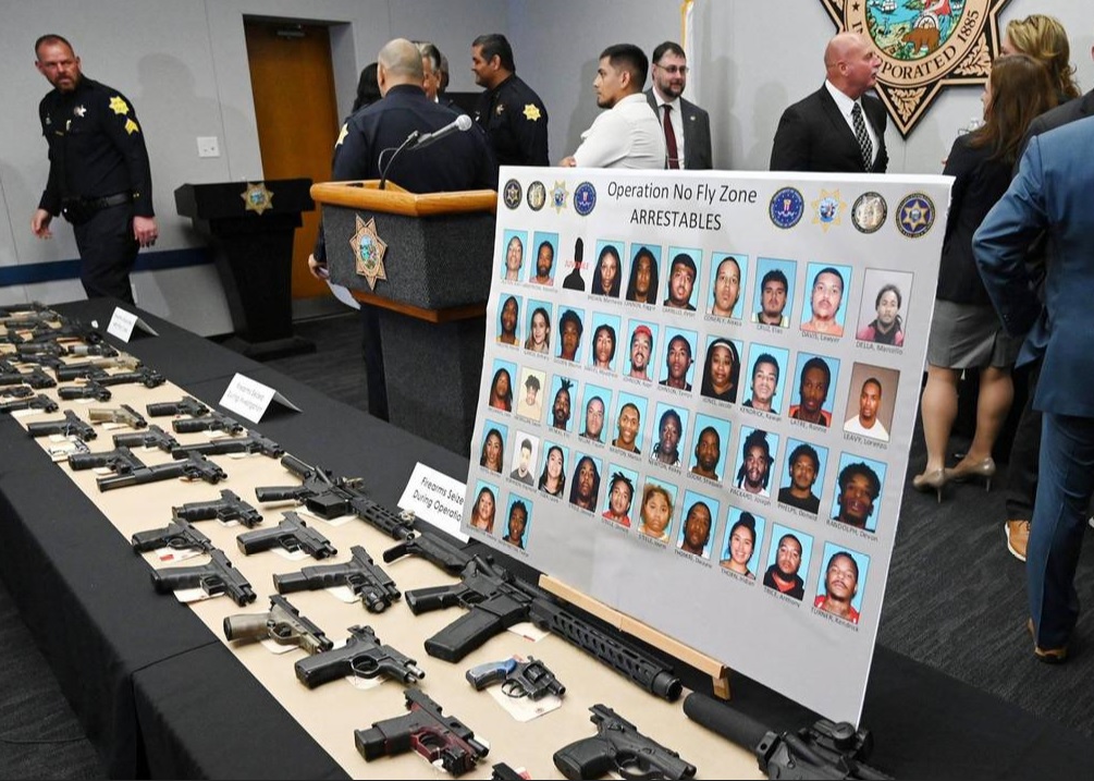 Fresno parole and others with table covered in seized guns.