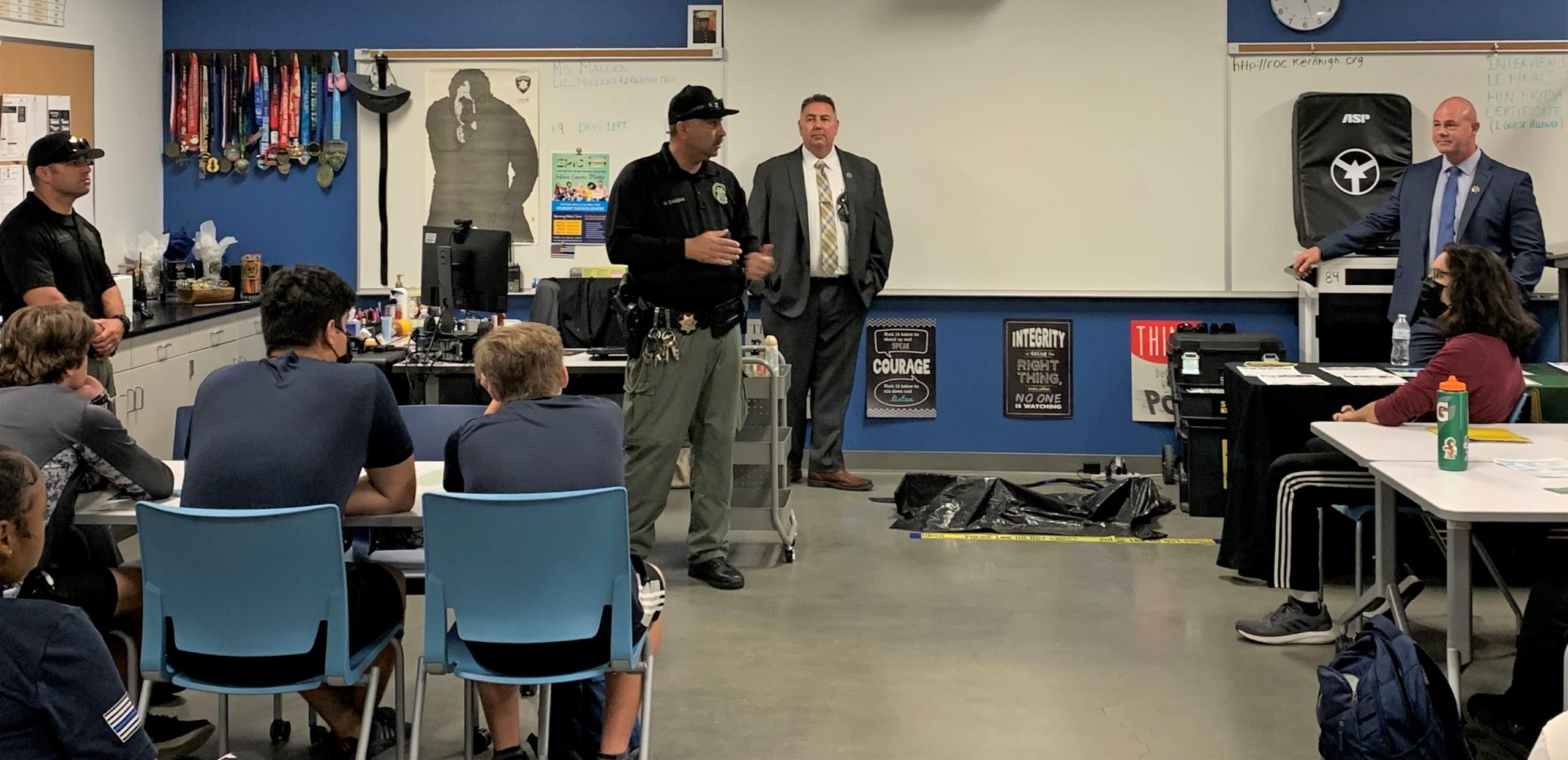 Officer and warden stand in front of class.