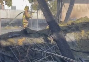 Firefighter sprays hot spots in burned out building.