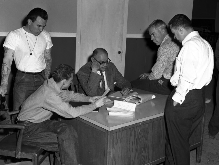 Five men around a desk.