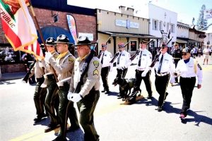 Mule Creek honor guard marches in uniform while carrying flags.